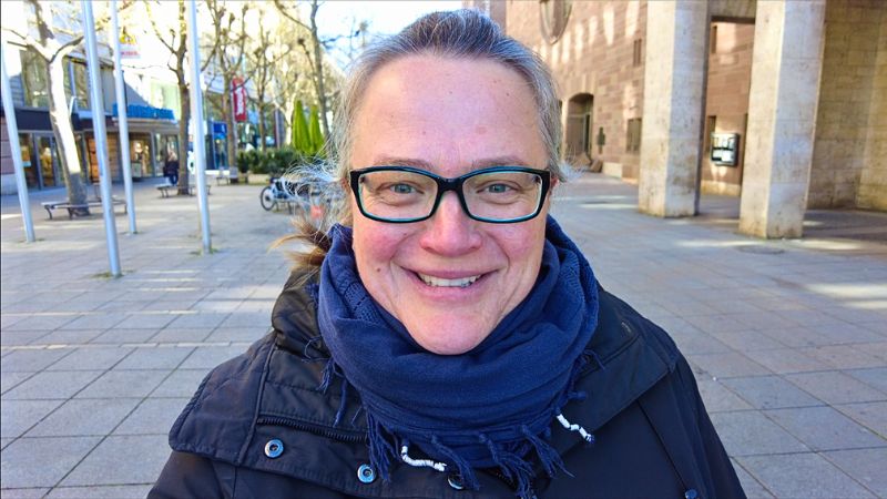 Reisebloggerin Stefanie Armbruster vom Reiseblog Steffistraumzeit steht lächelnd in einer Fußgängerzone mit Winterjacke und dunkelblauem Schal. Im Hintergrund sind Gebäude, Schaufenster und Bäume ohne Laub zu sehen – ein klarer Wintertag in einer Stadt. Das Bild symbolisiert ihre Leidenschaft für Slow Travel, authentische Begegnungen und individuelle Reisen, über die sie auf ihrem Blog berichtet