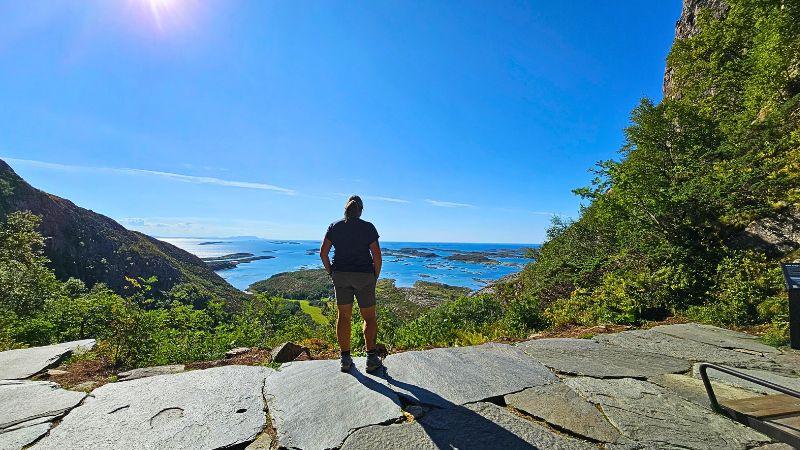 Eine Frau steht auf einem Felsen und seiht in die Ferne. Es ist die Aussicht vom Torghatten